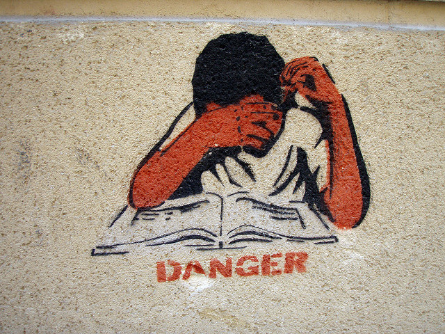 Un graffiti en el que se representa a un estudiante leyendo un libro sobre la palabra Danger